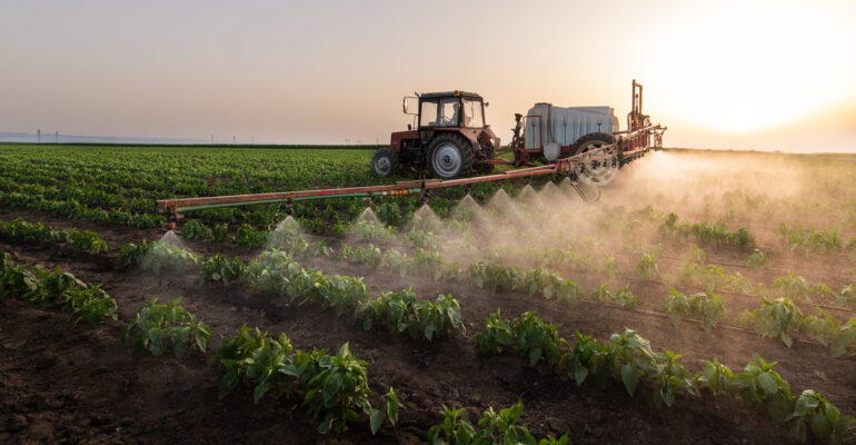 Tractor spraying pesticides on vegetable field  with sprayer at spring